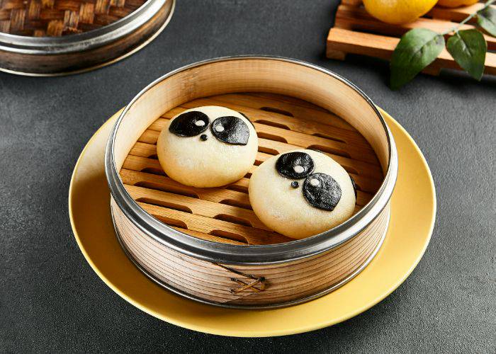 Two Taiwanese bao buns in an open steamer. They are decorated to look like pandas.